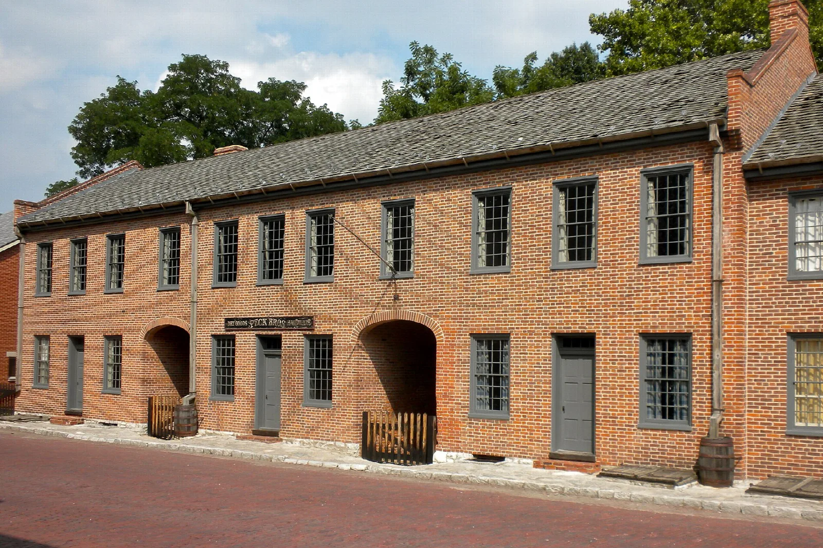 Two-story red brick buildings with a gray roof along a street