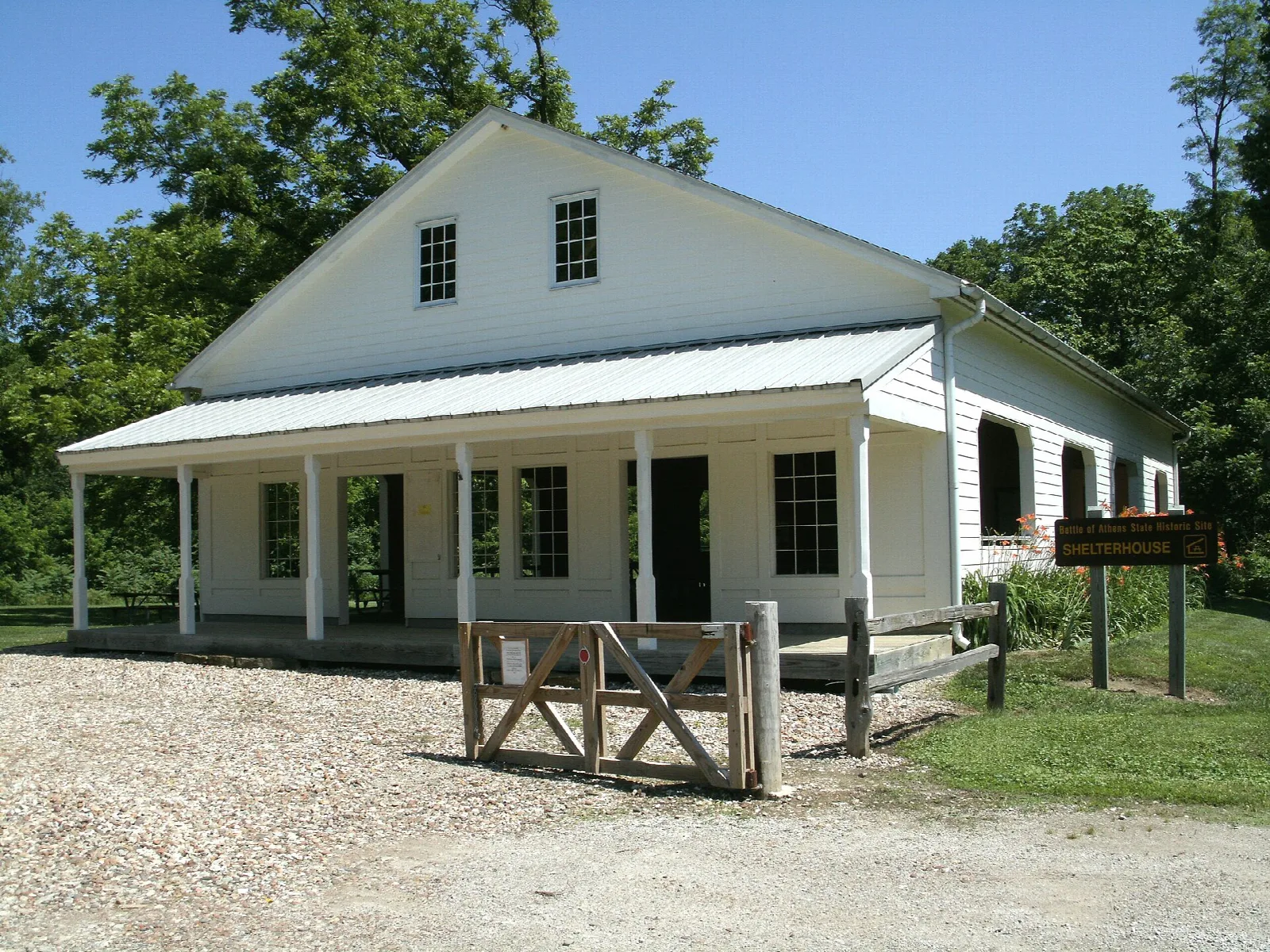 White historic building with a long front porch and gravel drive