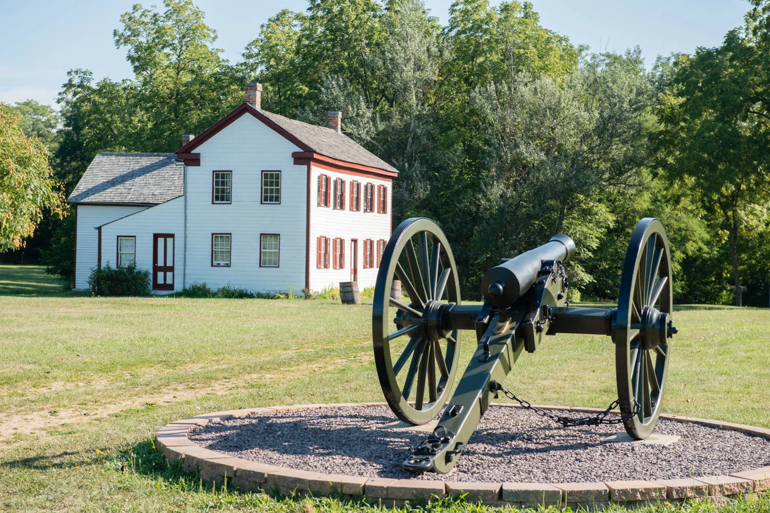 Cannon on a gravel ring in front of white historic buildings