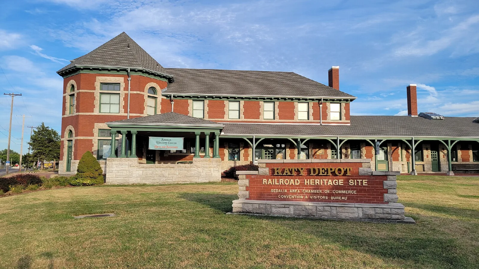 Red brick railroad depot with a heritage site sign in the lawn