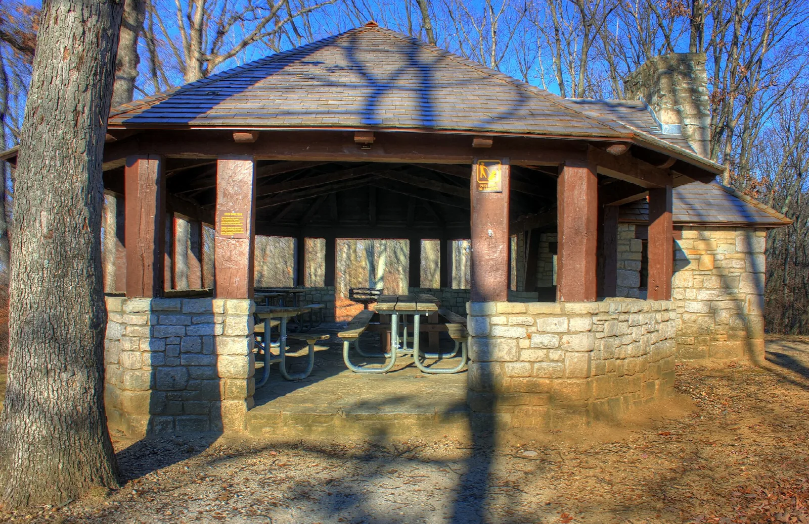 Stone and timber picnic pavilion in bare autumn woods