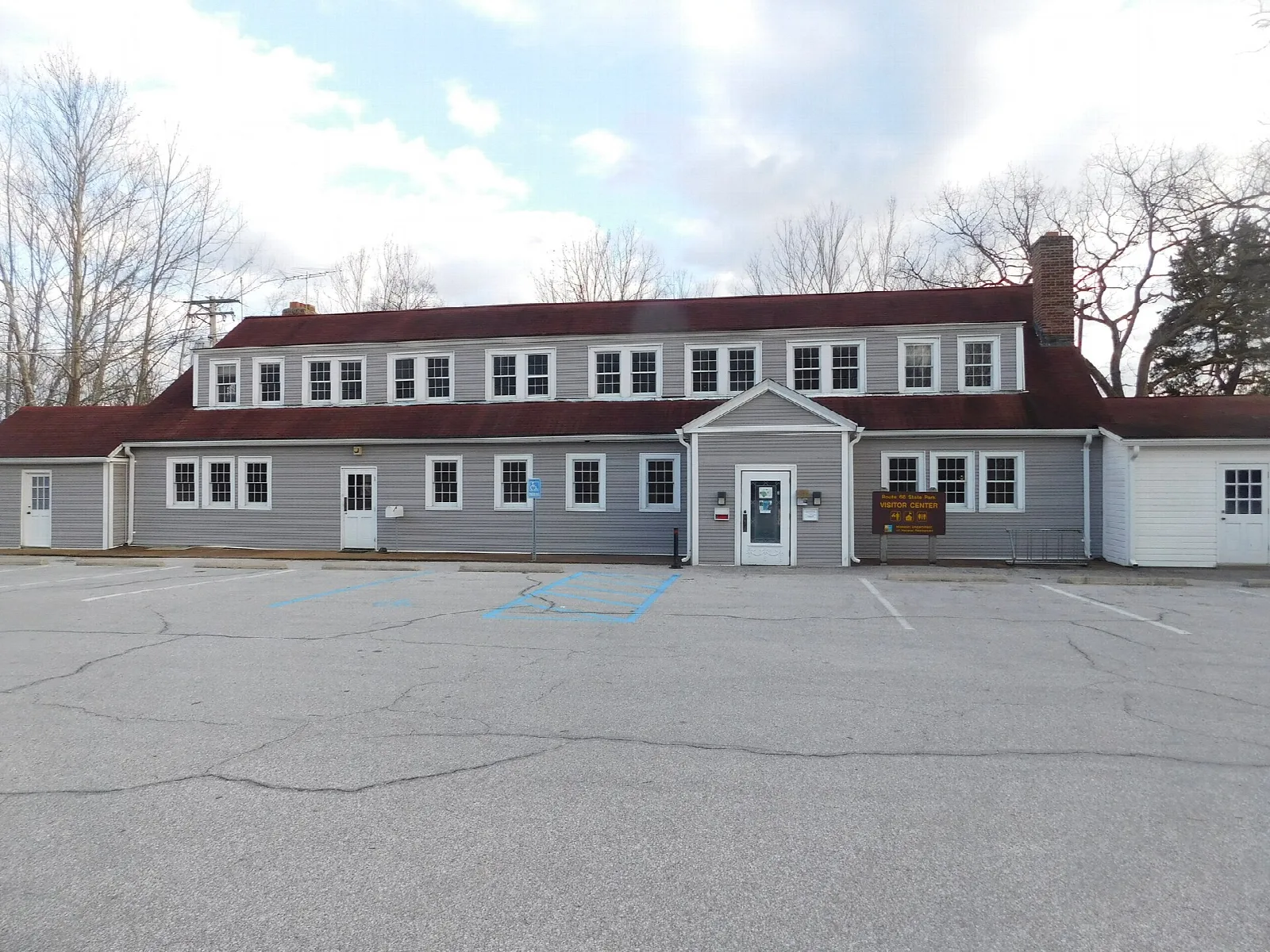Two-story gray roadhouse building with a red roof and a parking lot
