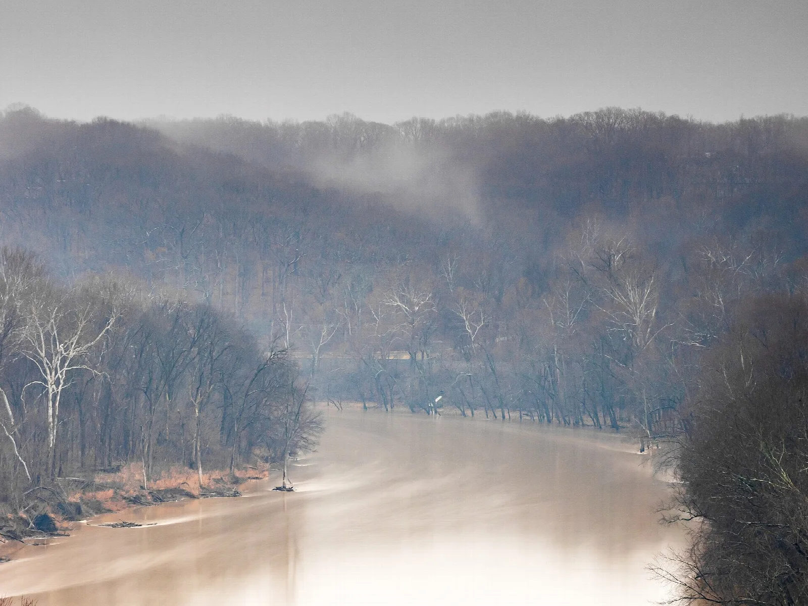 Foggy river bend between wooded hills