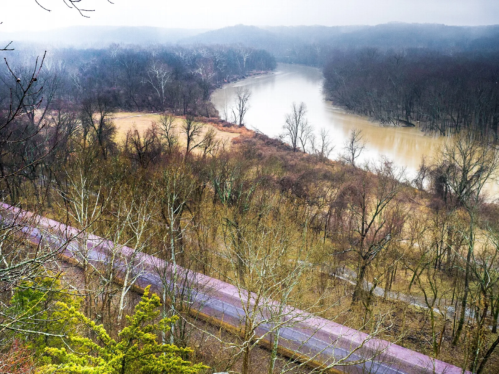River bend with misty hills and a railroad line along the bank