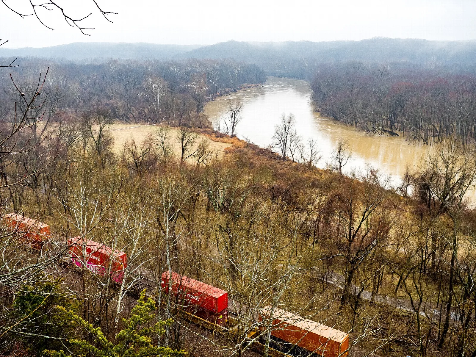 Wide river bend seen from a bluff with a train on tracks below