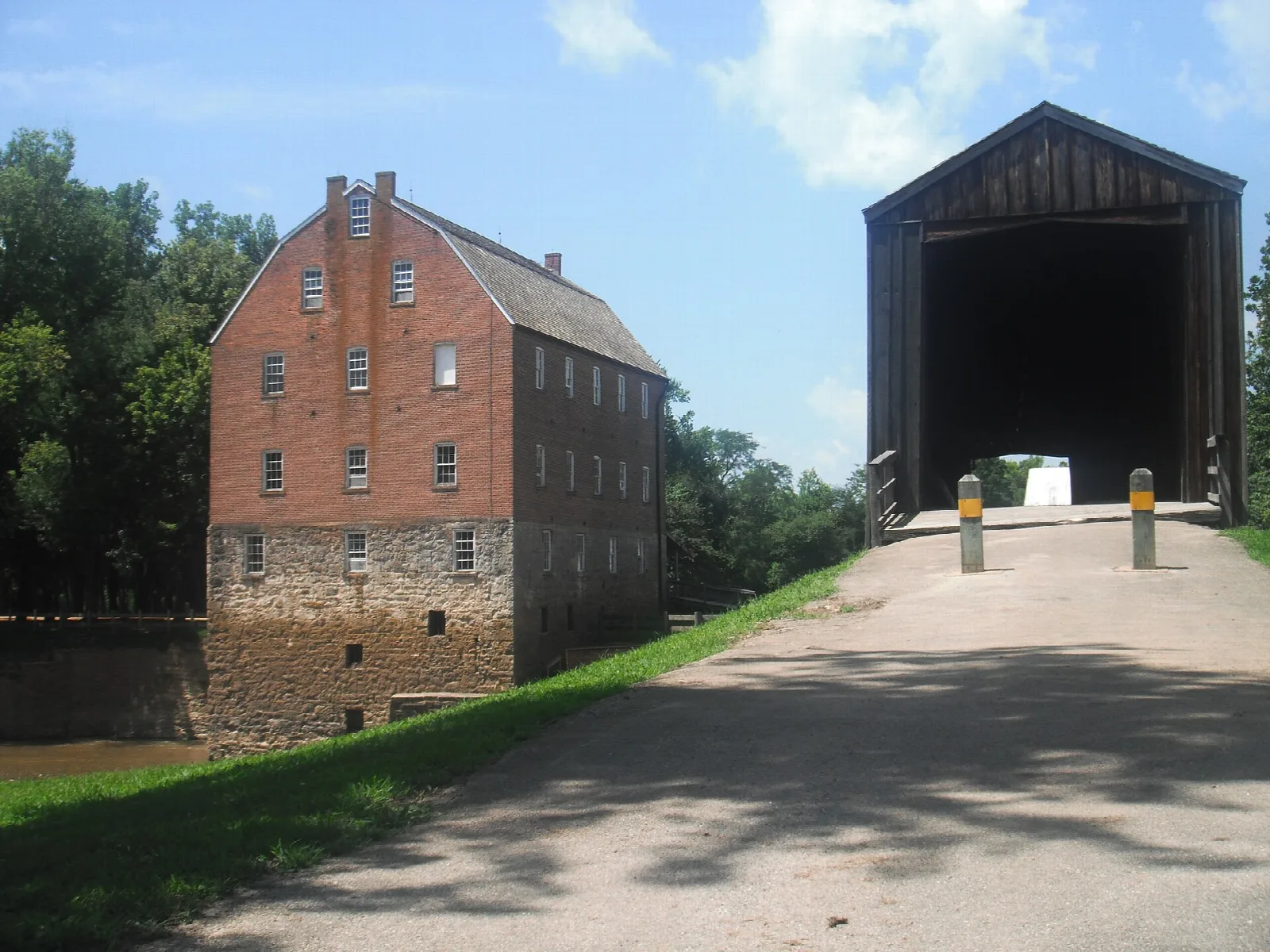 Brick mill beside a road leading into a covered bridge