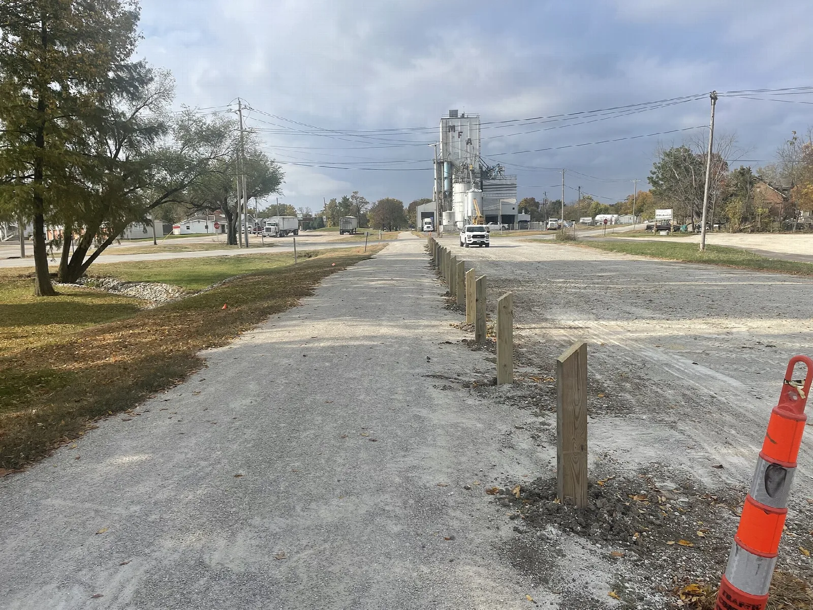 Gravel trail edged with posts running along a street toward a grain elevator
