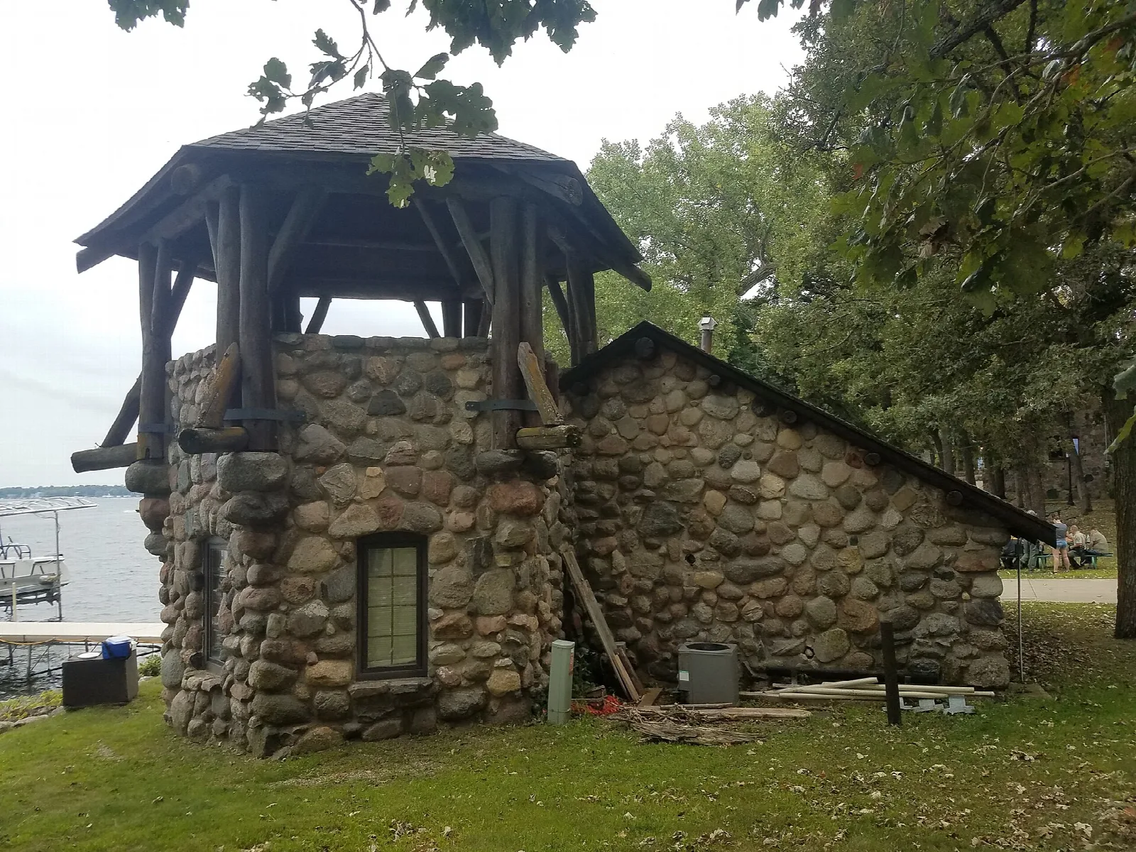 Fieldstone boat house with a small gazebo-style roof beside the lake
