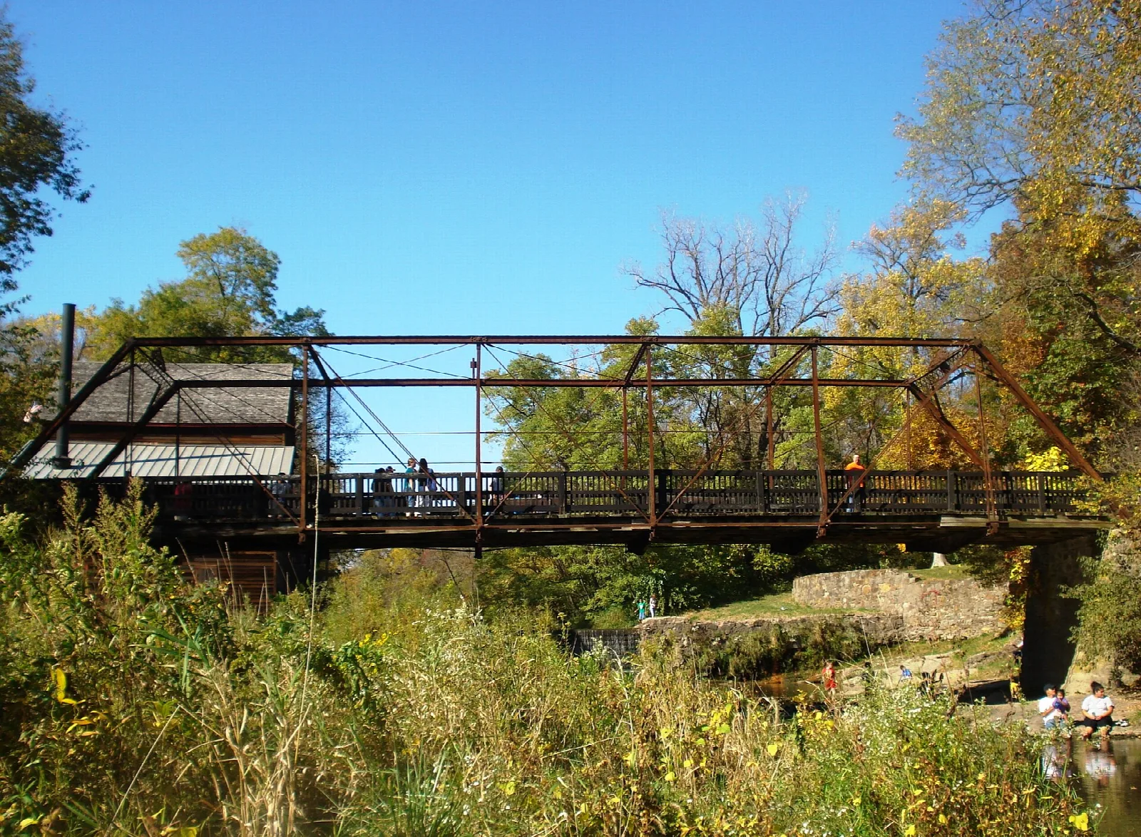Old iron truss bridge over a creek with fall color on the trees