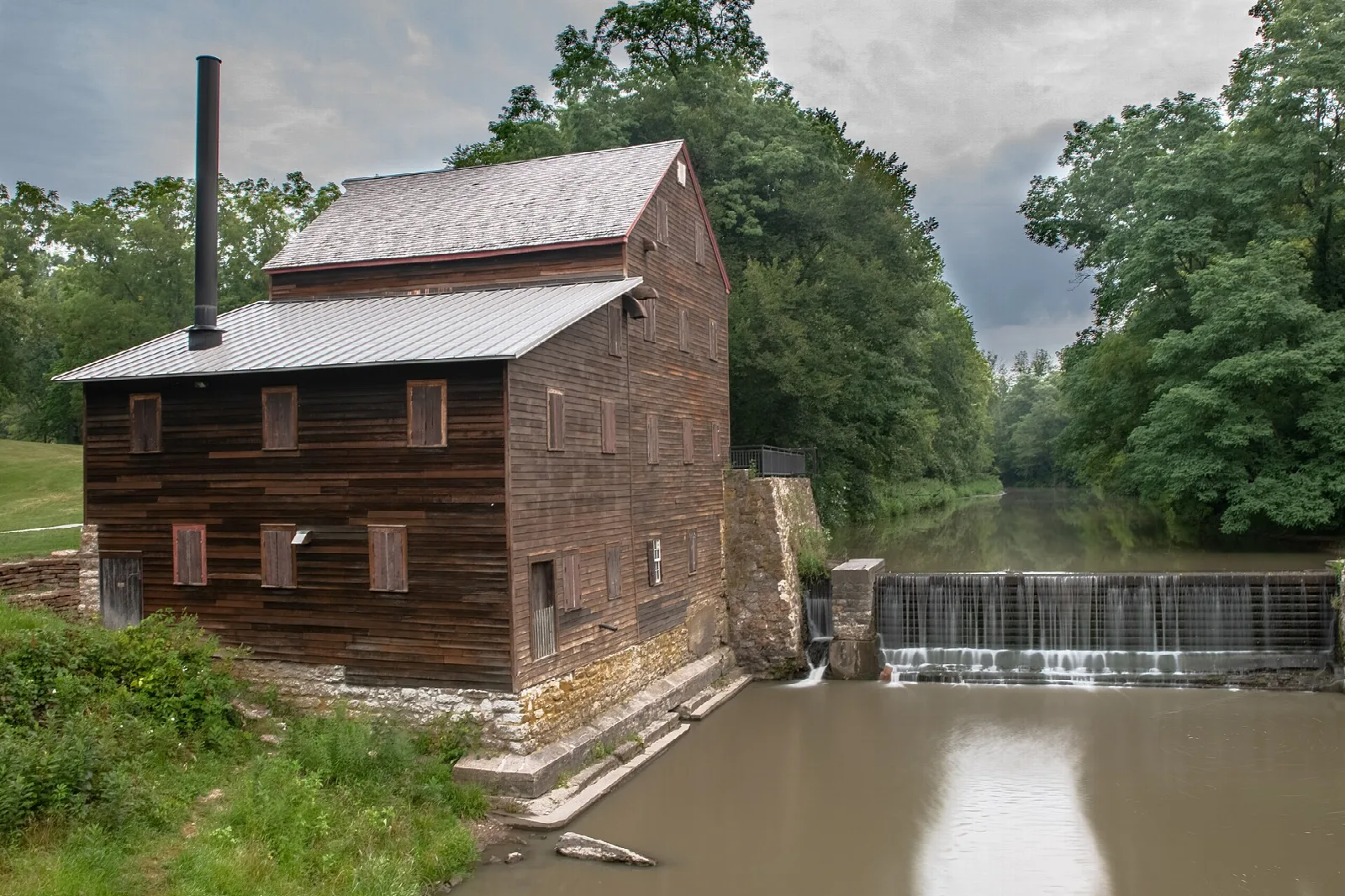 Wooden mill building above a low waterfall on the creek