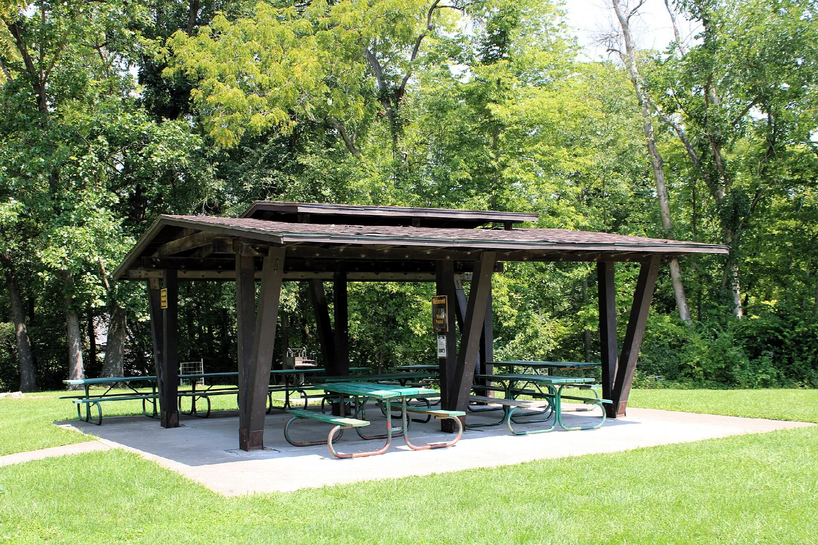Open wooden picnic shelter on a lawn among trees