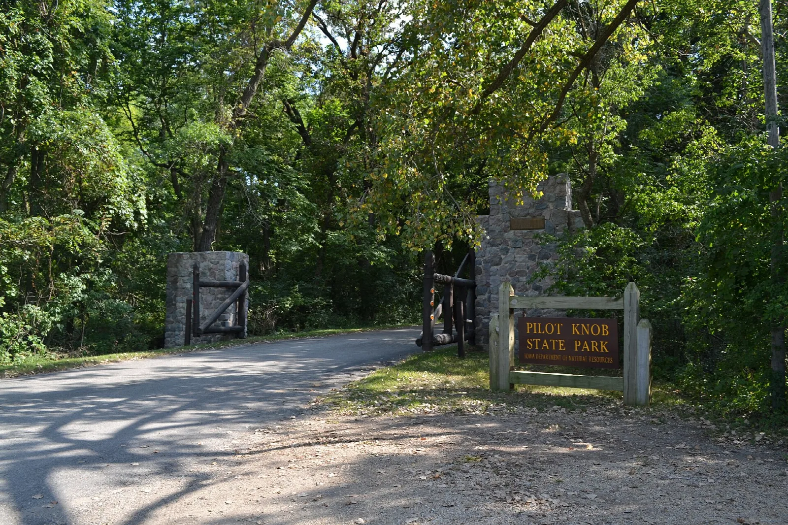 Gravel road and stone portals with a park entrance sign in the woods