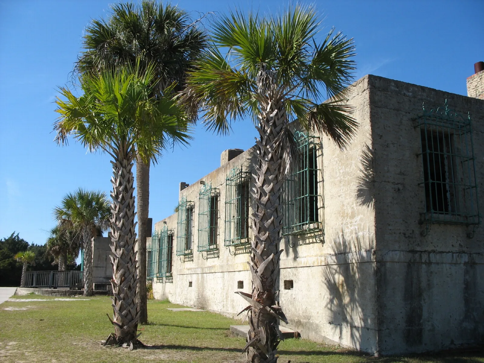 Stone building with barred windows beside tall palmetto palms