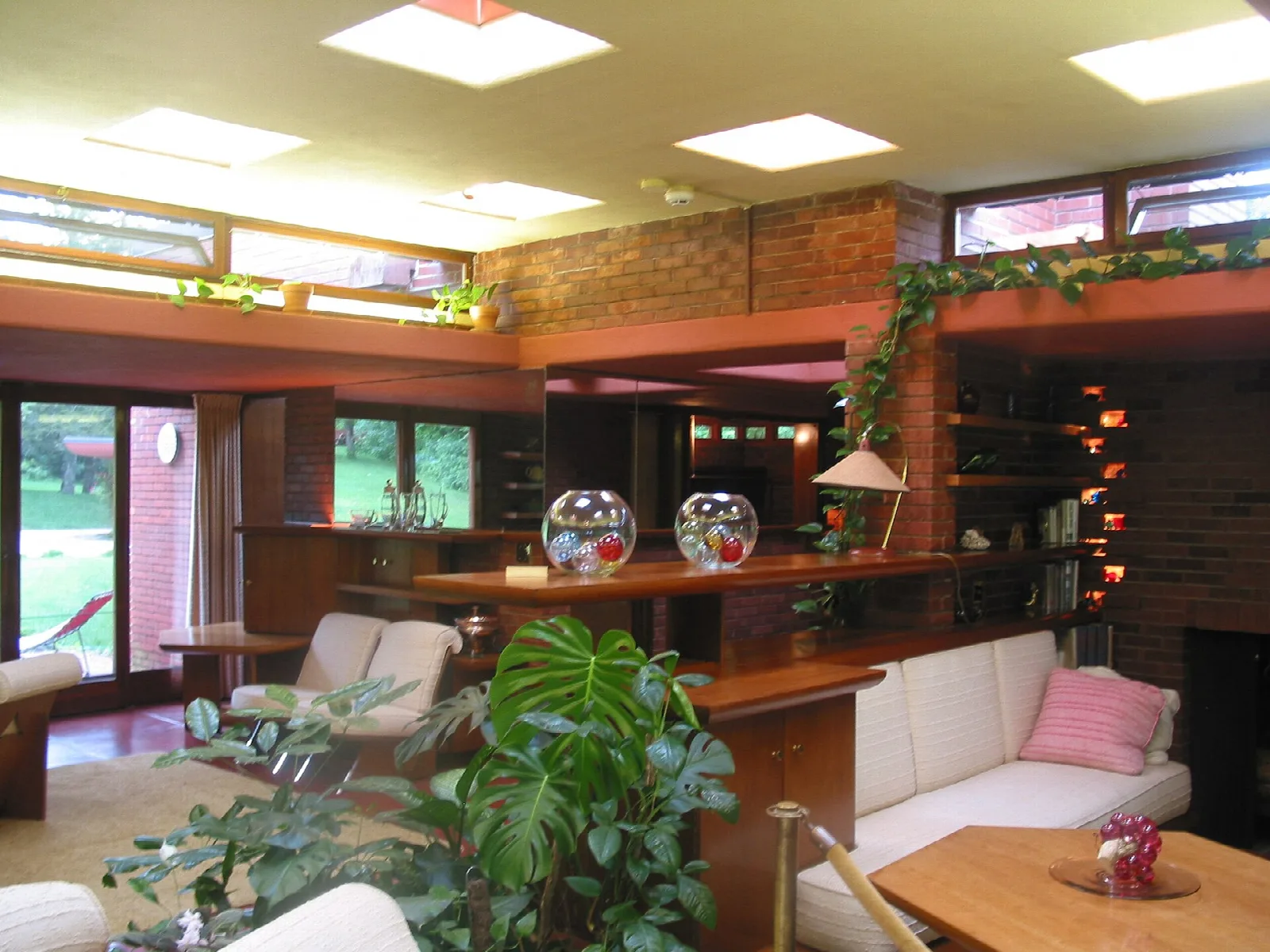 Living room with brick walls, skylights, white sofas and wood shelves