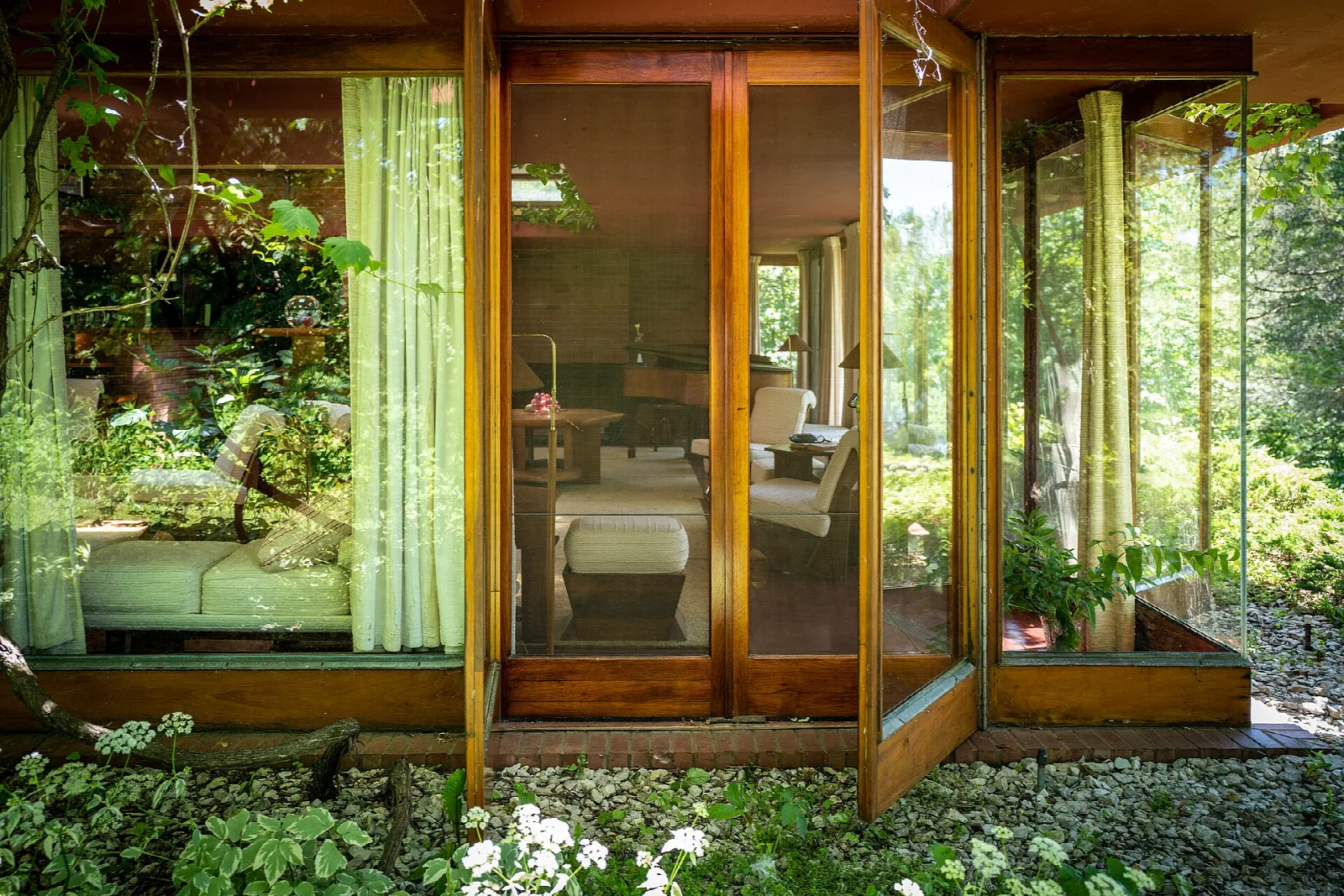 Glass wall of the house with plants and an interior seating area visible