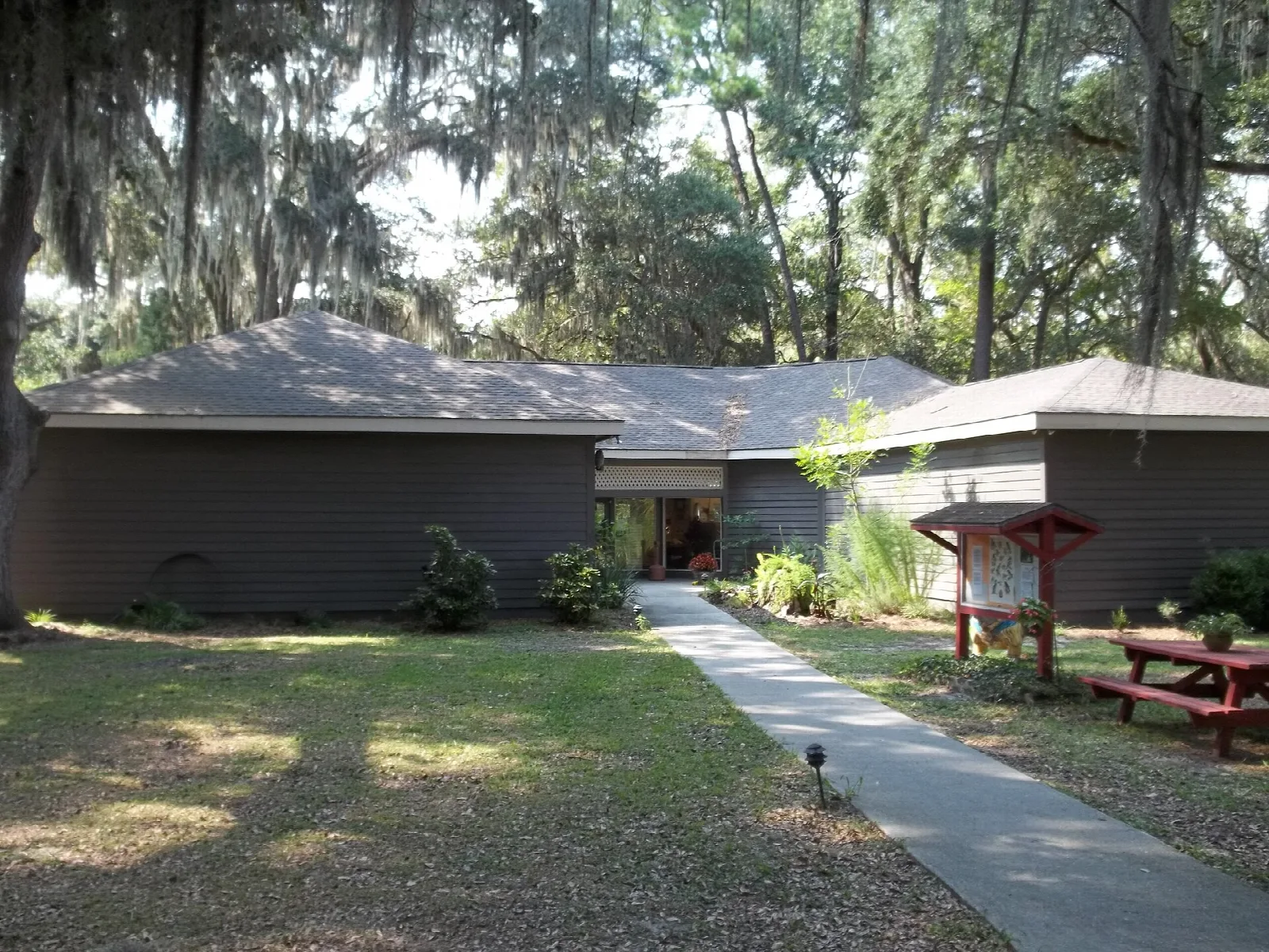 Low brown buildings and a paved walkway under trees