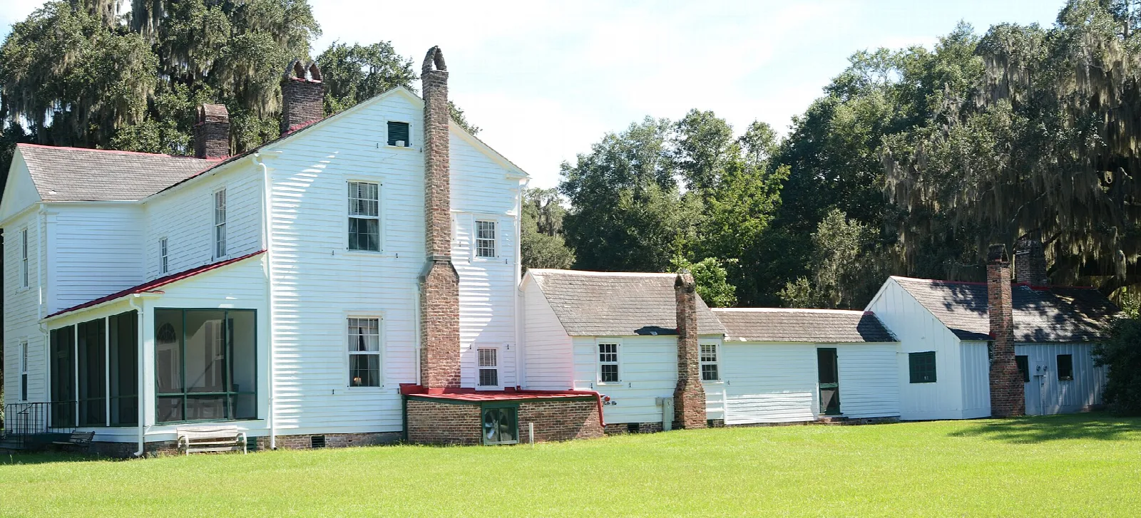 Side of a white house with a detached kitchen building beside it