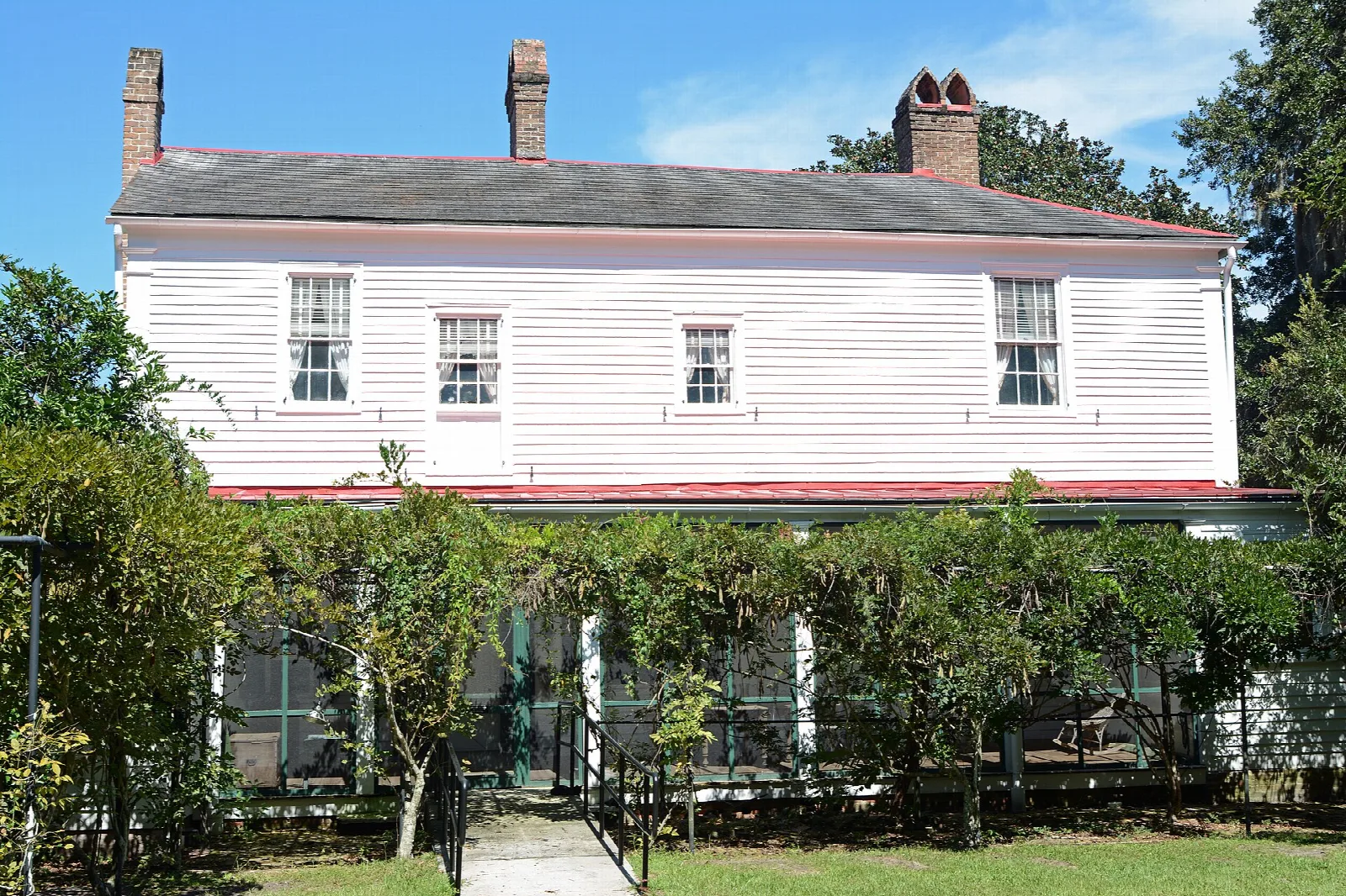Front of a pale two-story house with a vine-covered porch