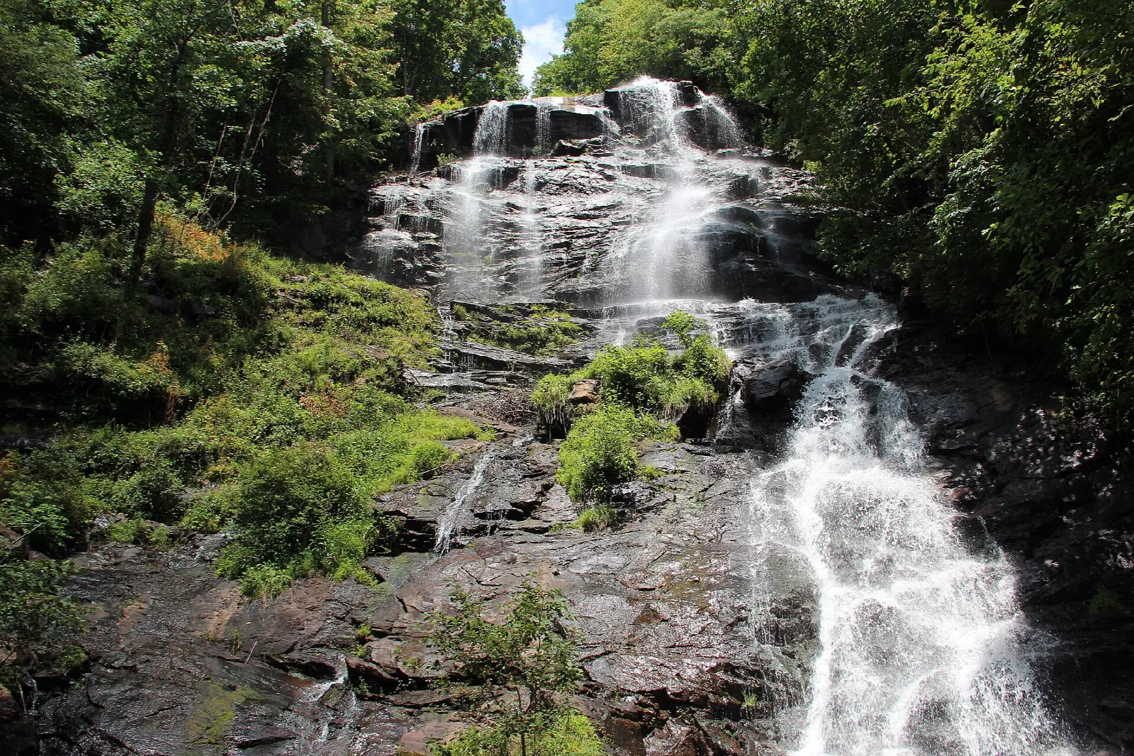 Tall waterfall tumbling down a rocky, forested slope