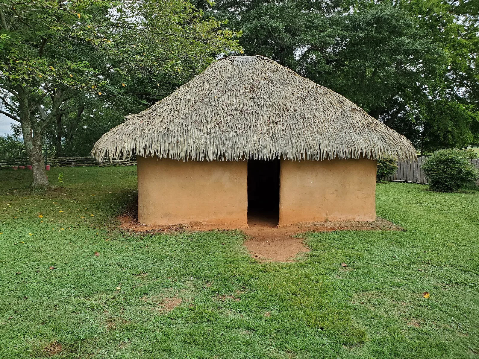Thatched-roof clay hut on a green lawn