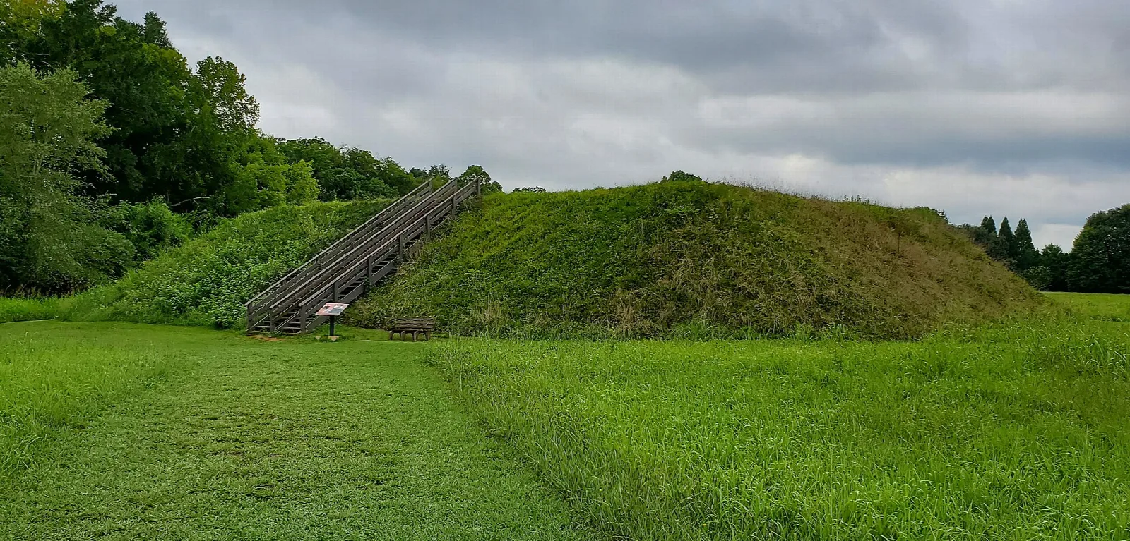 Low grassy mound with a staircase under a cloudy sky
