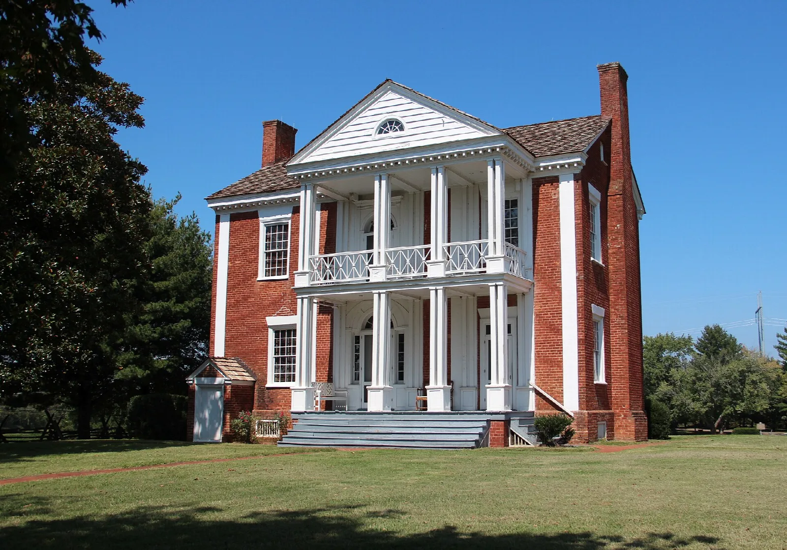 Two-story brick house with white columned porch on a green lawn