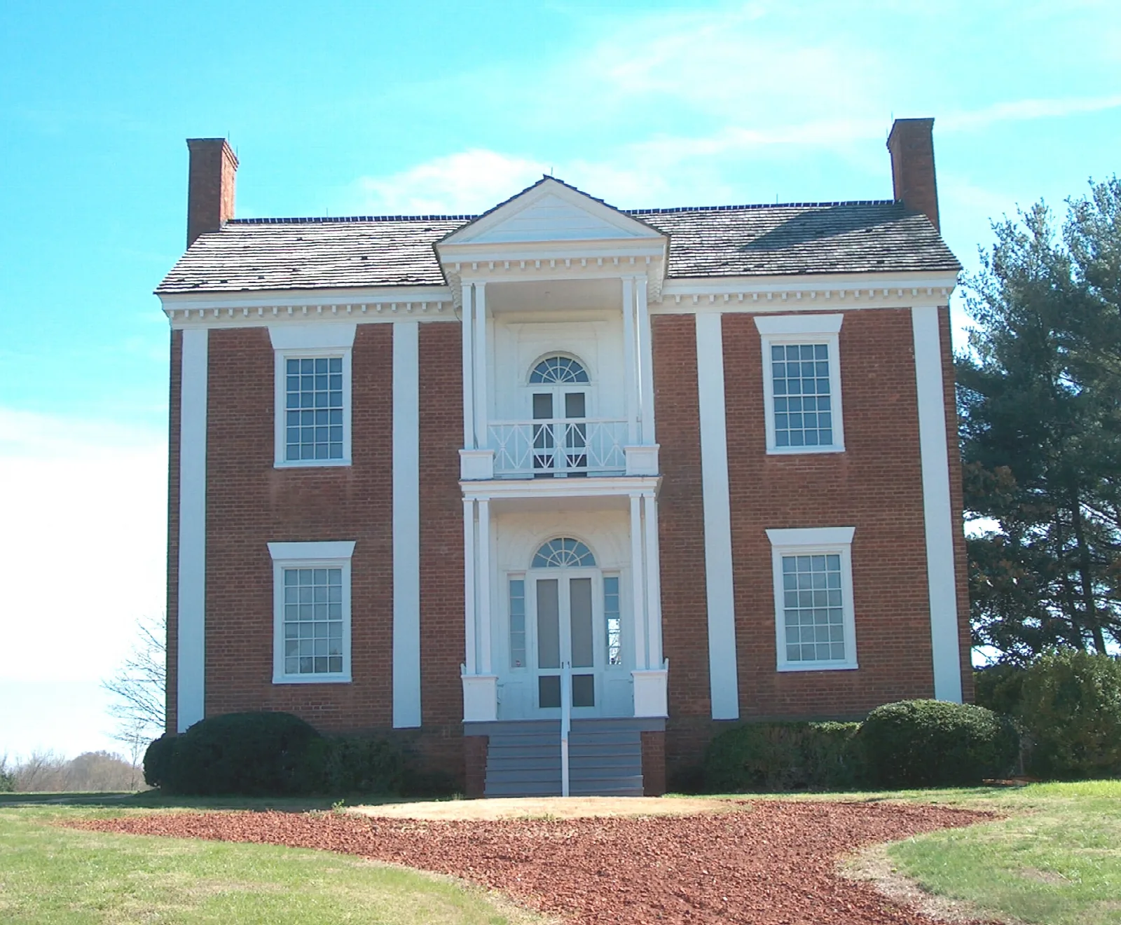 Front of a brick house with a two-level white portico