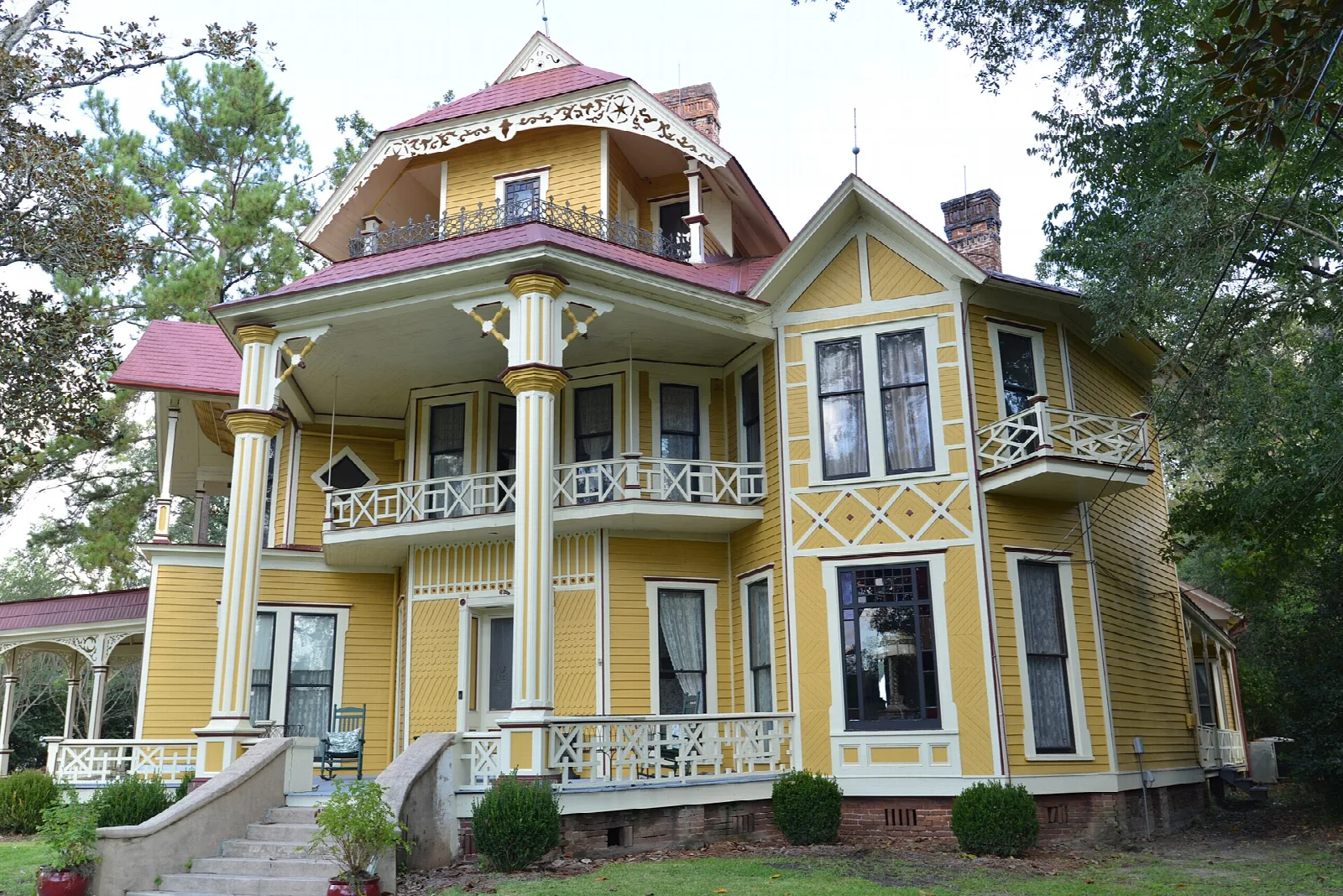 Yellow Victorian house with white porch columns and a tower