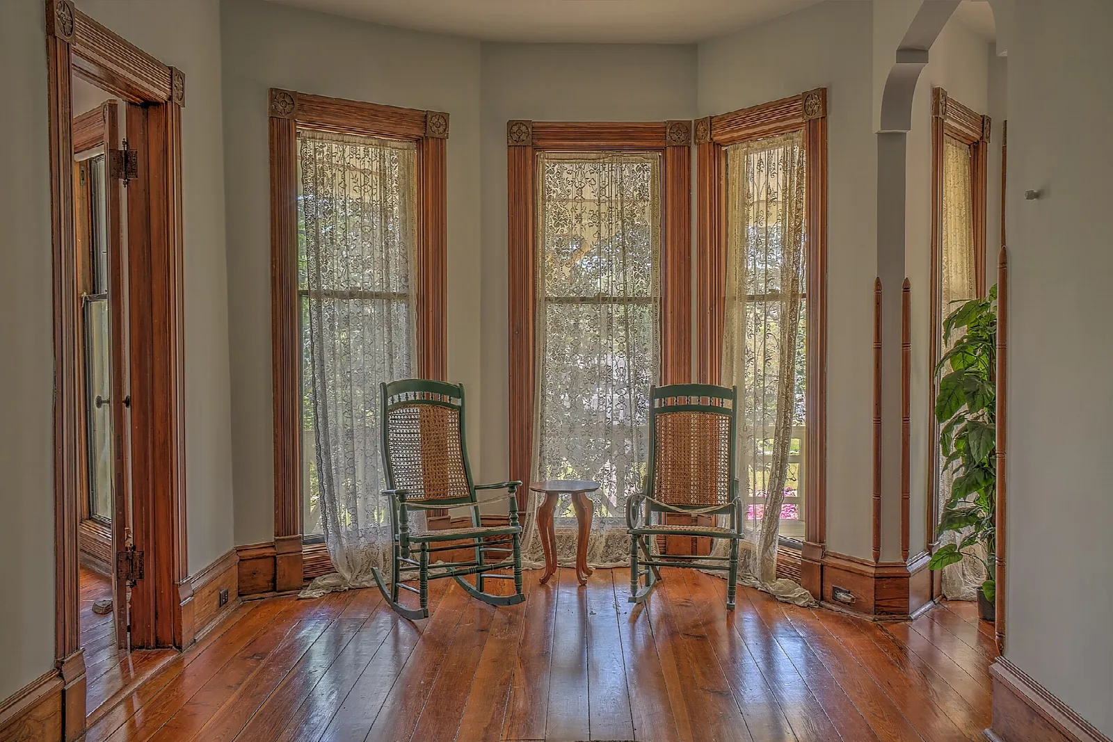 Sunlit room with bay windows, lace curtains and two rocking chairs
