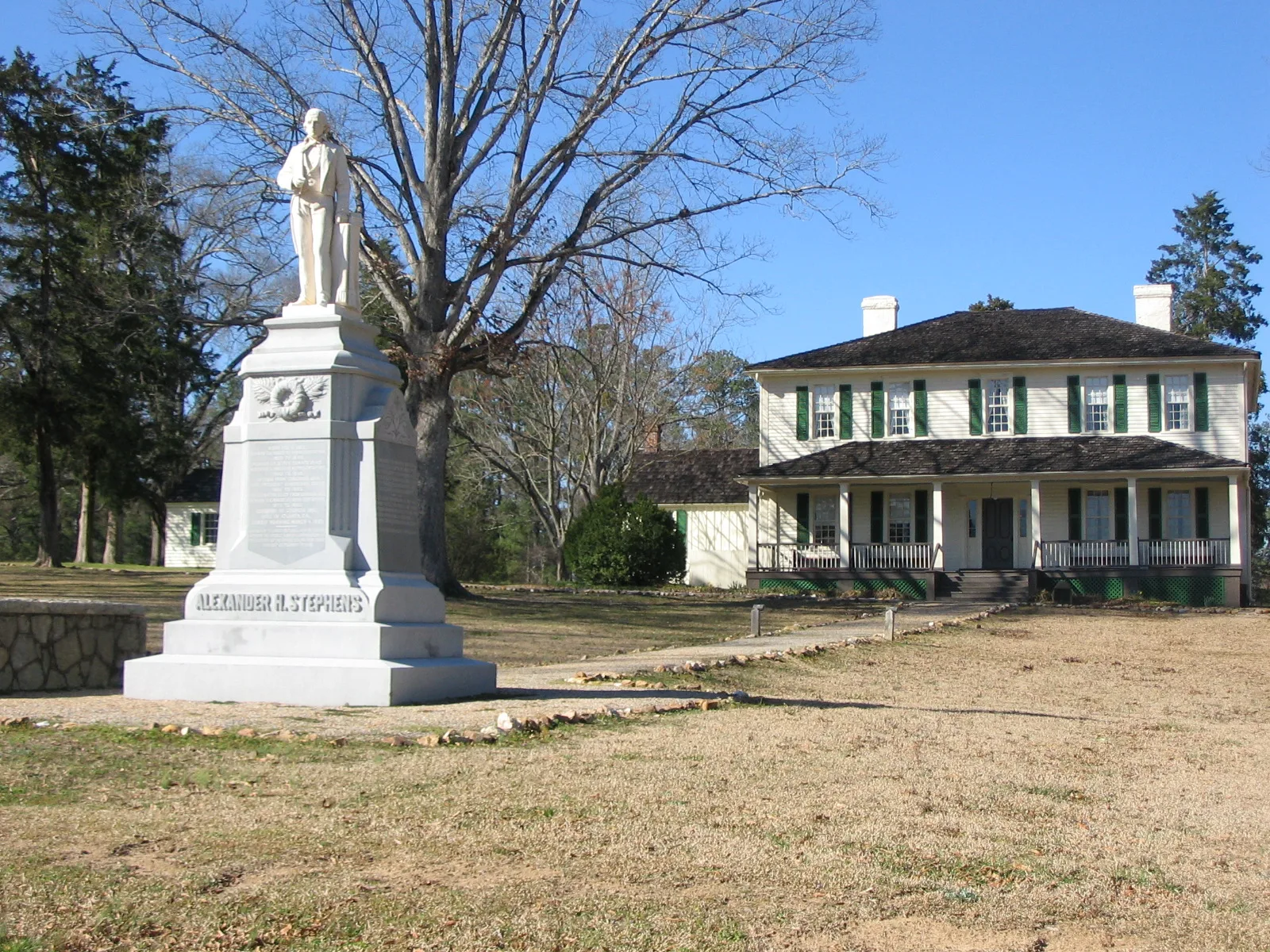 White monument in front of a two-story house on a lawn