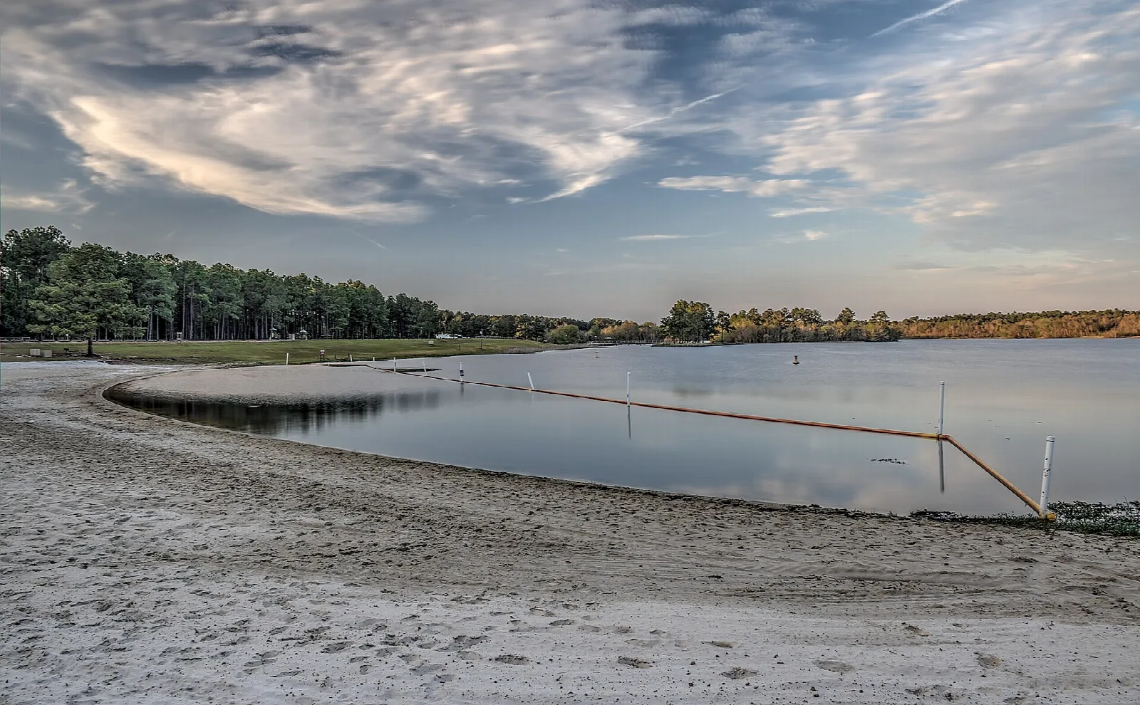 Sandy beach curving along a lake under a cloudy sky