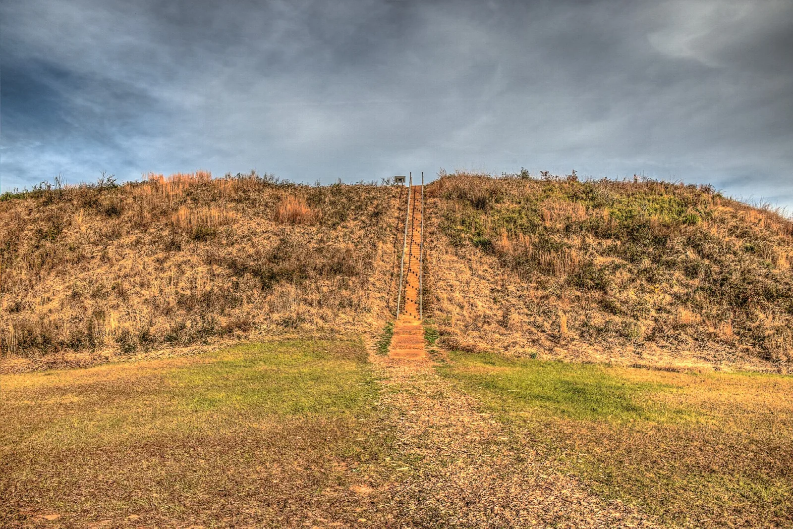 Large grassy temple mound with a narrow stairway up the middle