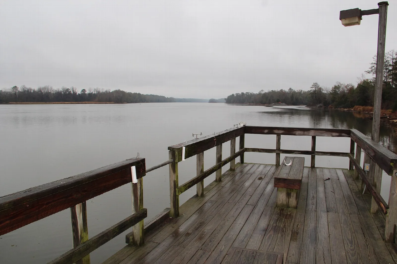 Wooden deck with railings over a wide gray lake