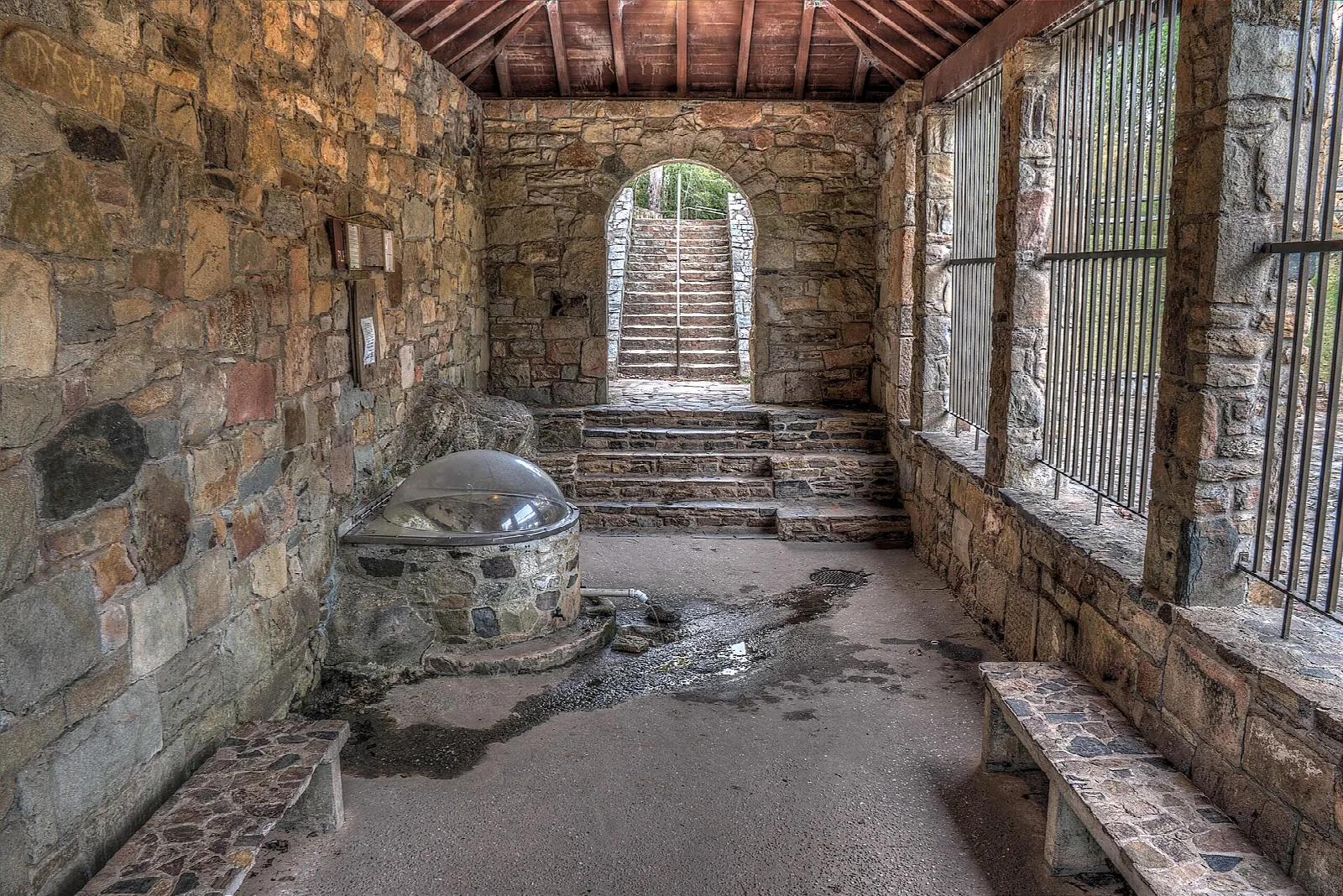 Stone-walled spring house with steps leading up to an arched doorway and a domed spring basin
