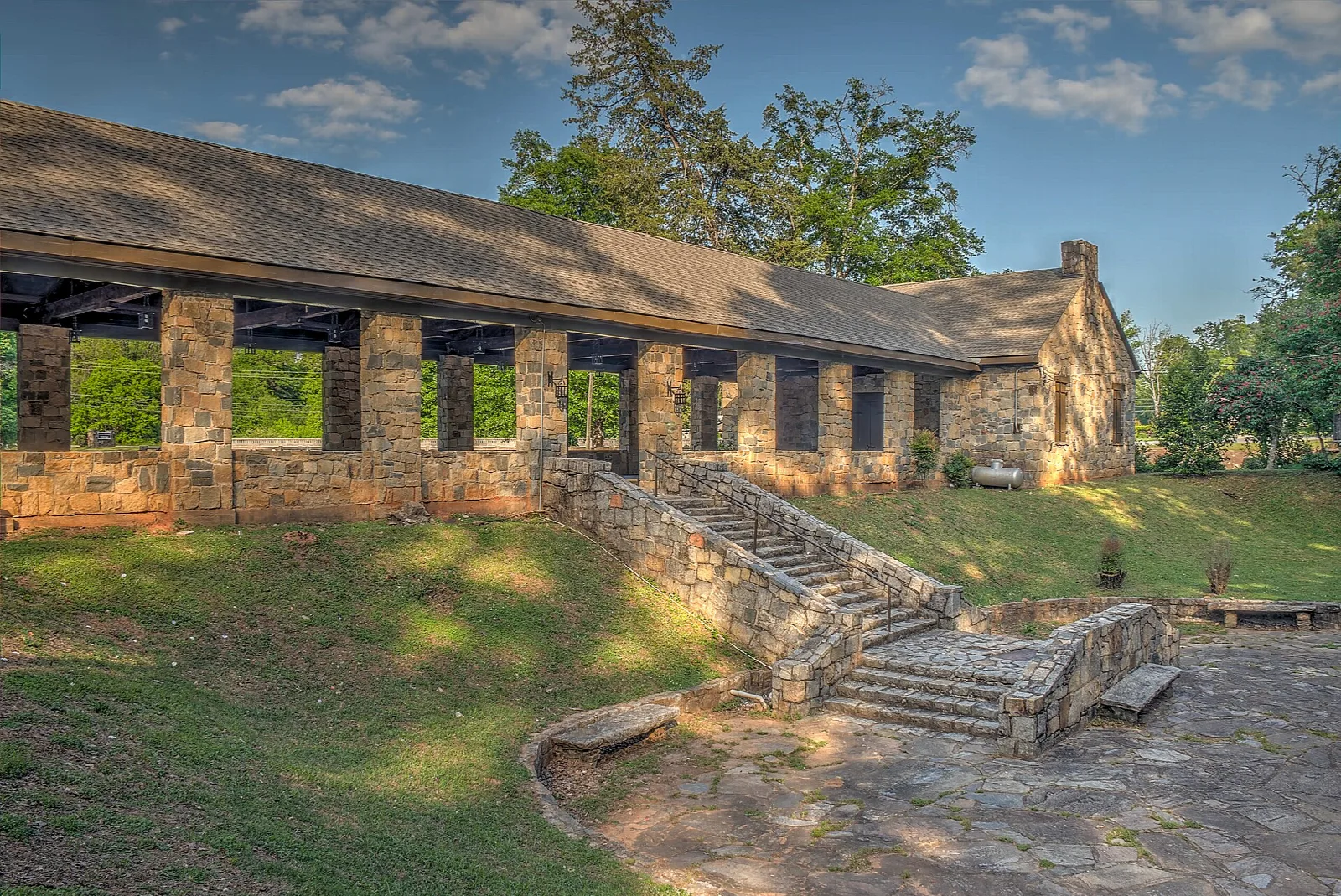 Long stone pavilion with a low roof, stone steps and green lawn