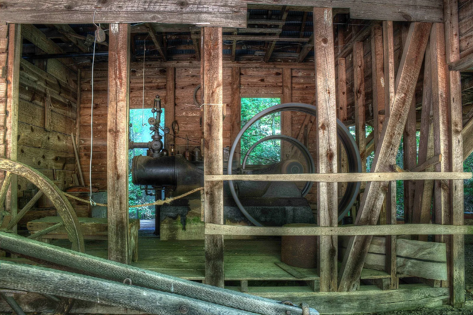 Inside a wooden engine house with a large flywheel and belts