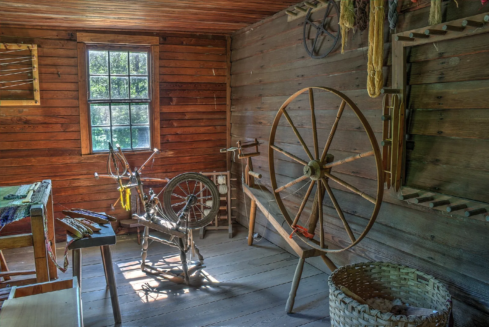 Wood-paneled room with a large spinning wheel and a window