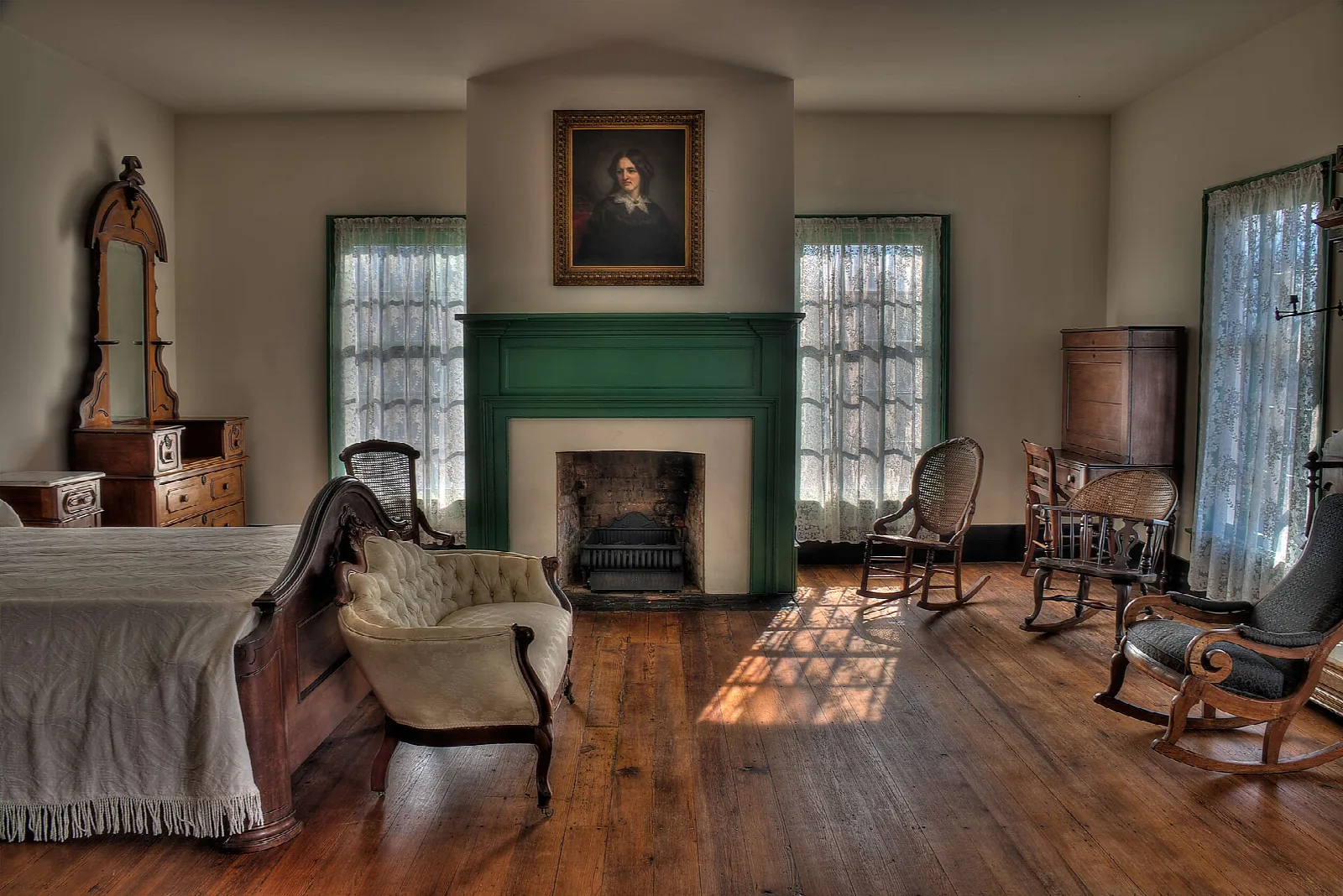 Bedroom with a four-poster bed, green fireplace surround and wood floor