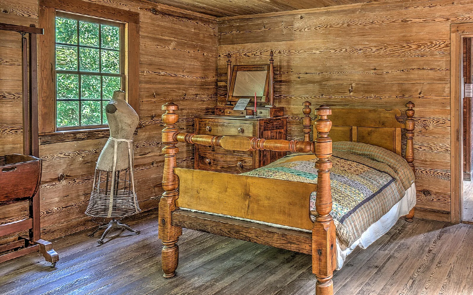 Plank-walled bedroom with a wooden bed, quilt and a dress form