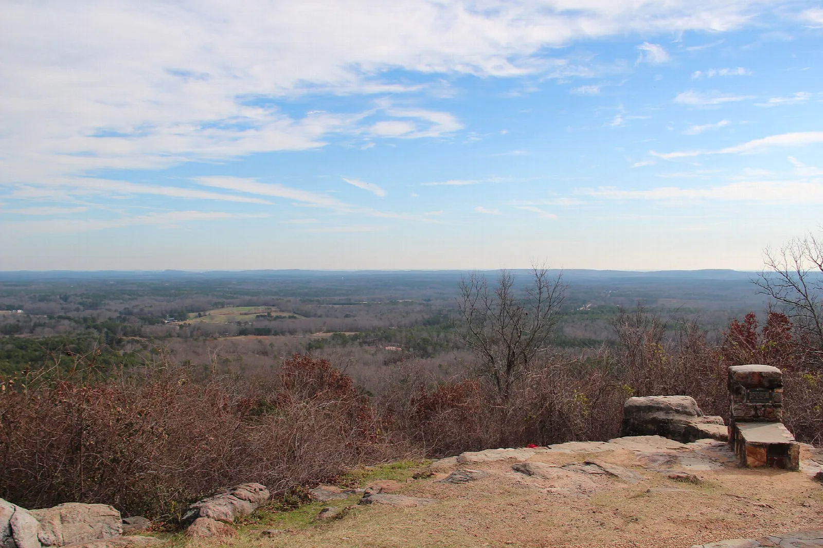 Stone benches on a rocky overlook above a hazy forested valley