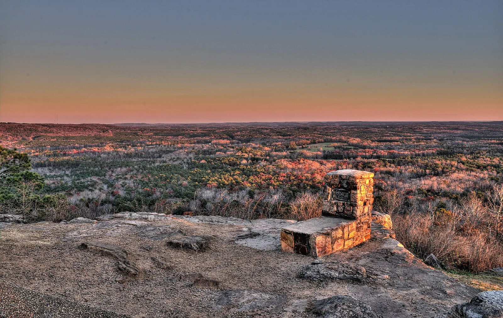 Rocky overlook with stone benches under an orange glow on the horizon