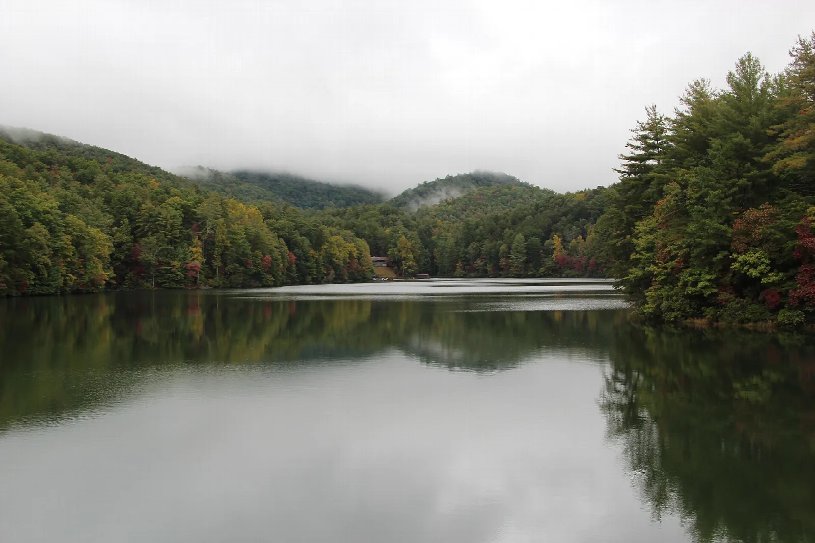 Misty forested hills reflected in a calm lake