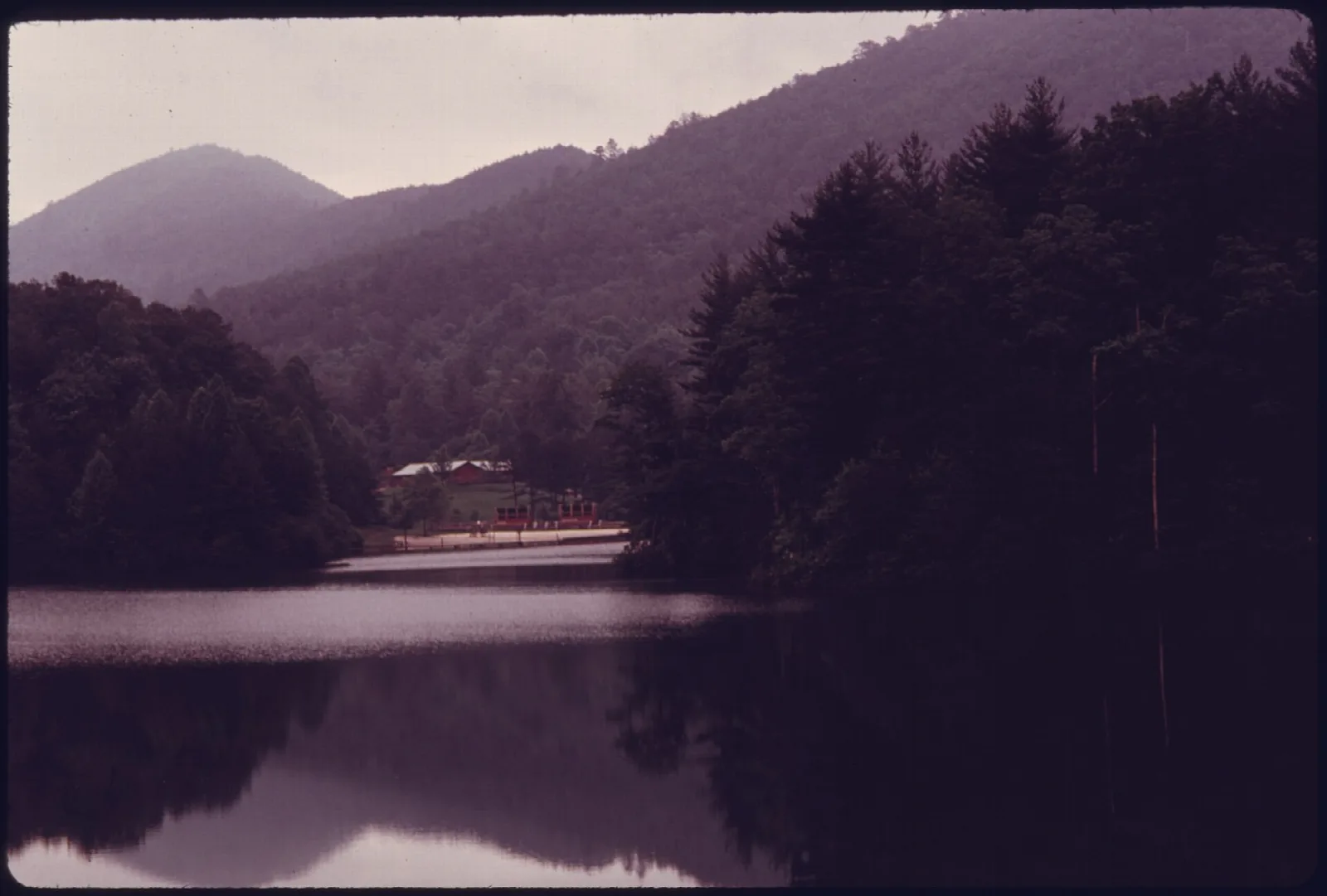 Vintage photo of a lake in a mountain valley with a small building on the far shore