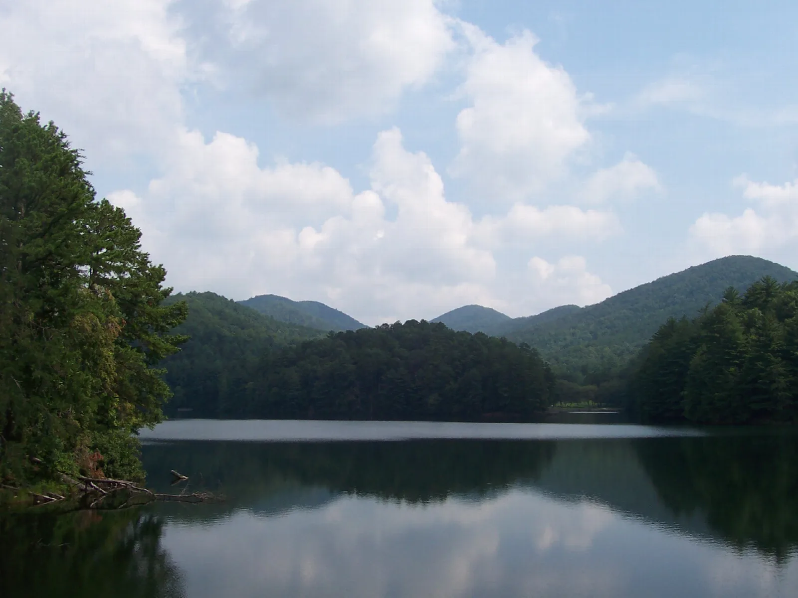Lake with forested ridges and clouds behind
