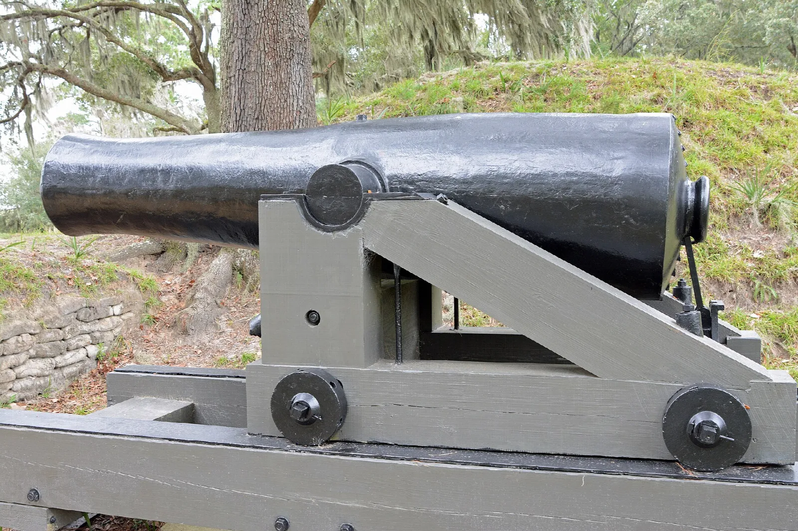 Black cannon on a gray carriage in front of an earthen mound