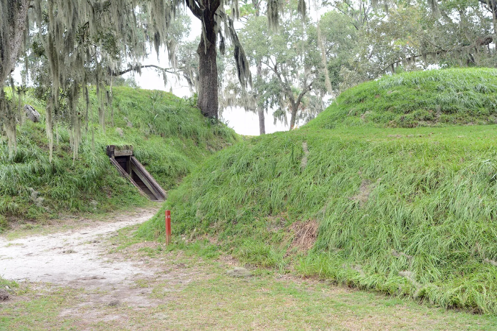 Earthen fort walls with a dirt path and wooden bombproof entrance