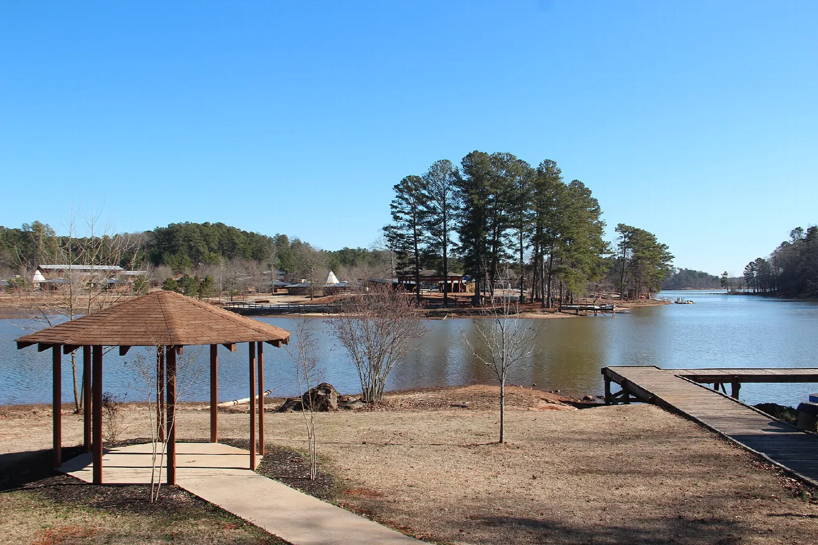 Wooden gazebo and dock beside a lake with pine trees