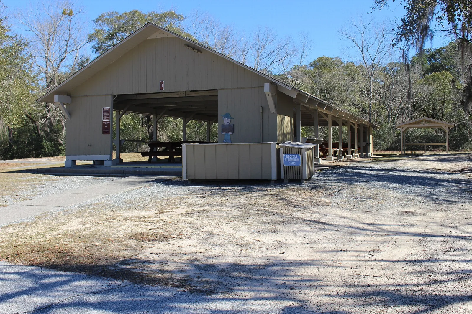 Large open picnic shelter beside a gravel lot