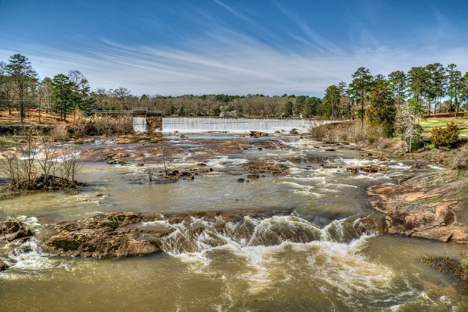 Cascades over rocks with a dam in the distance