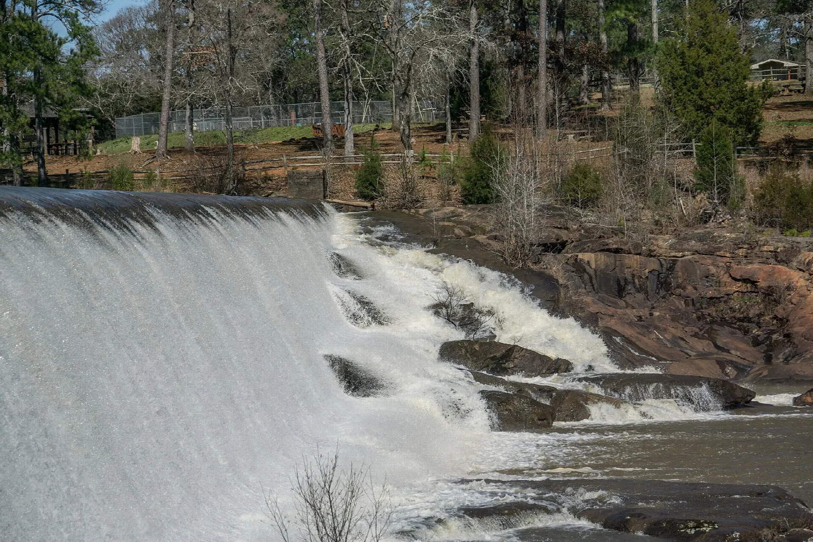 Wide waterfall spilling over a dam into rocks